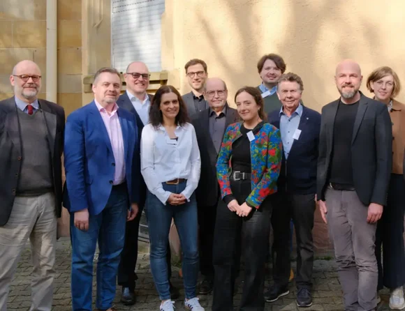 Gruppenfoto von Männern und Frauen vor einer Hausfassade