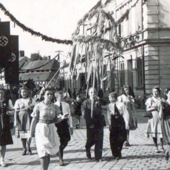 Ein Festumzug auf einer Straße. Menschen in Trachten tragen eine Erntedankfestkrone.