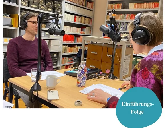 Ein Mann sitzt einer Frau an einem Tisch gegenüber. Beide tragen Kopfhörer und sprechen in Mikrofone.